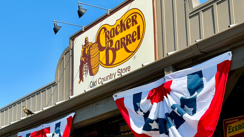 A close-up of the Cracker Barrel sign with a patriotic banner hanging below.