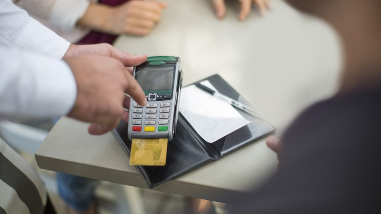 Restaurant server presenting a billing machine to a customer