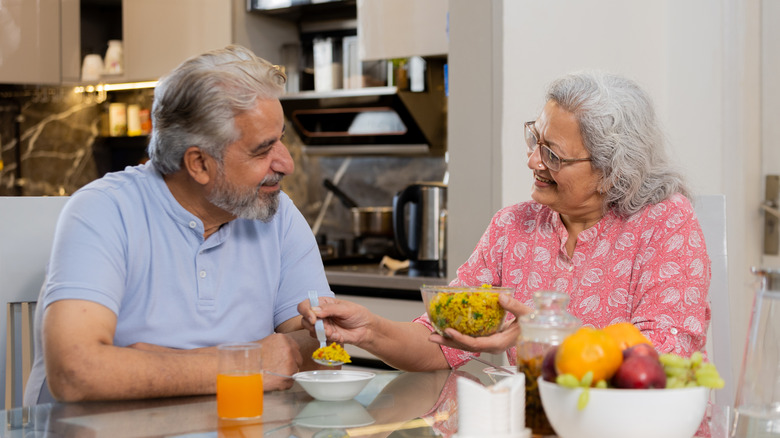 Happily retired senior couple eating food together