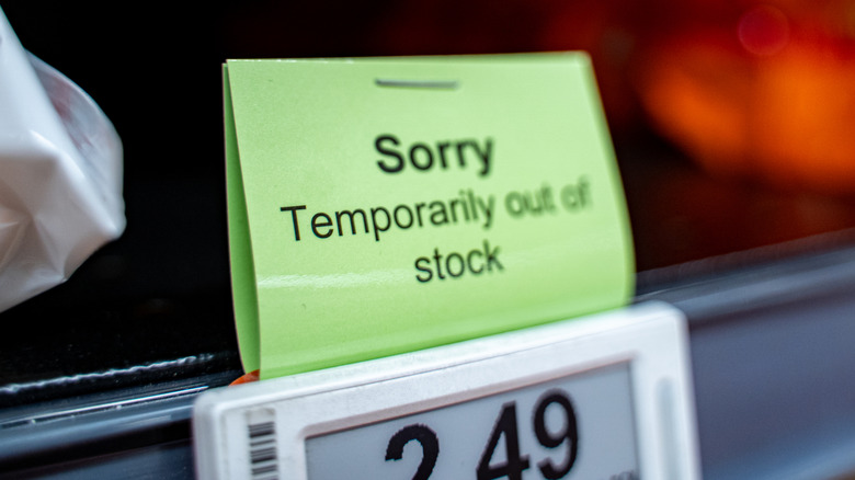 A small sign attached to a price tag on a store shelf that reads sorry temporarily out of stock