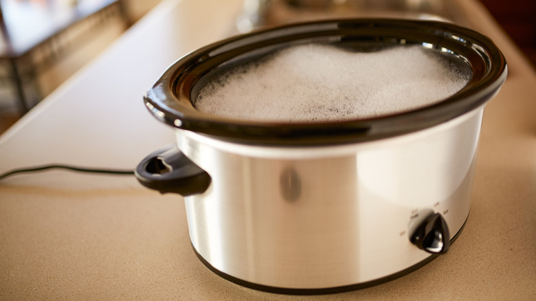 A slow cooker soaking with soapy water to clean it