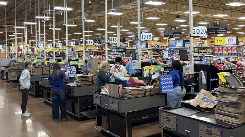 A photo spanning the entire Kroger checkout area with two lanes open, Kroger customers and workers are in the shot