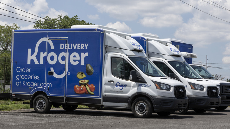 An outside shot of three Kroger delivery branded trucks sitting empty in a parking lot