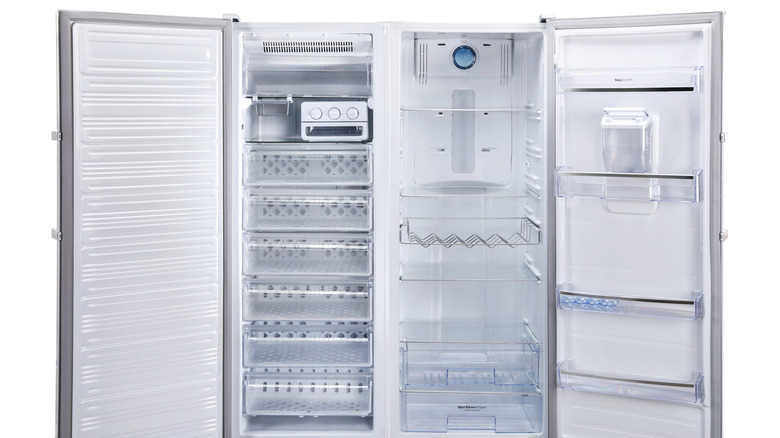 An open, empty side-by-side refrigerator