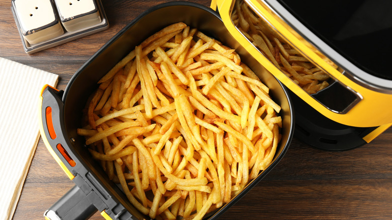 An air fryer basket slightly over filled with french fries