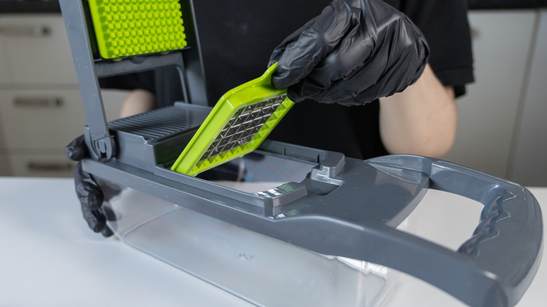 A gloved hand assembling a vegetable chopper