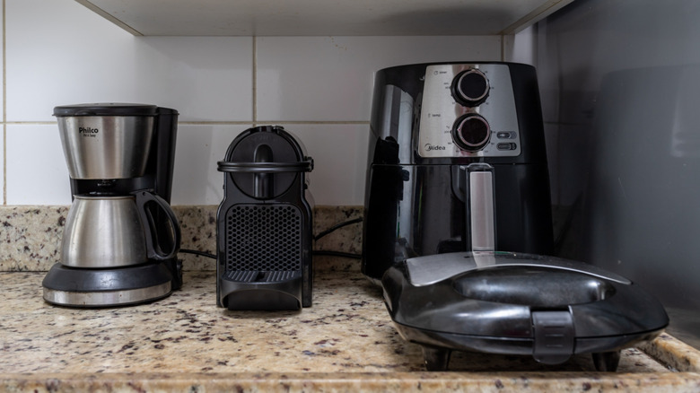a crowded countertop with an air fryer and other kitchen appliances