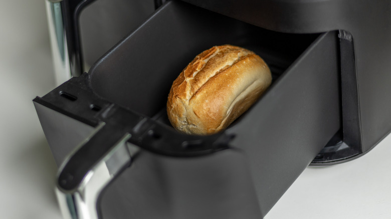 A single browned roll in an air fryer basket