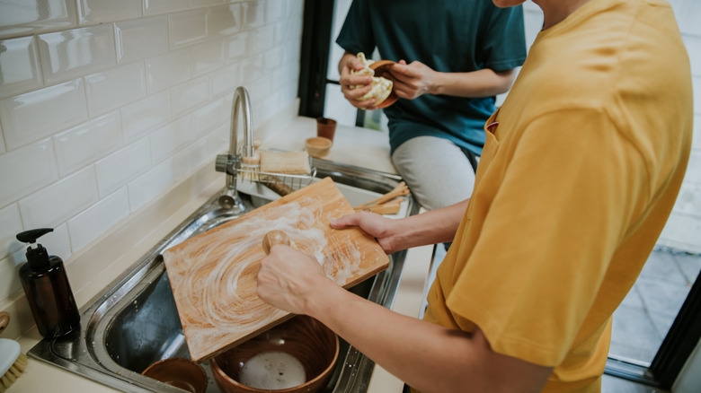 Man washing wooden cutting board