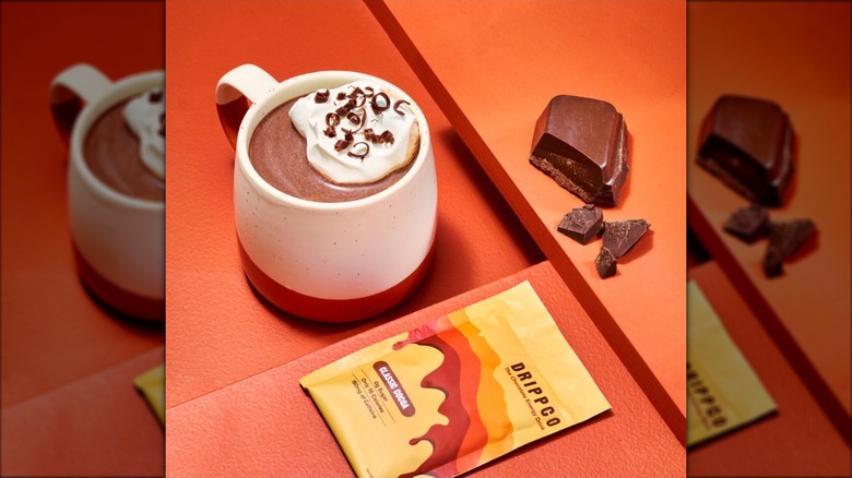 A cup of hot chocolate near a hunk of chocolate.