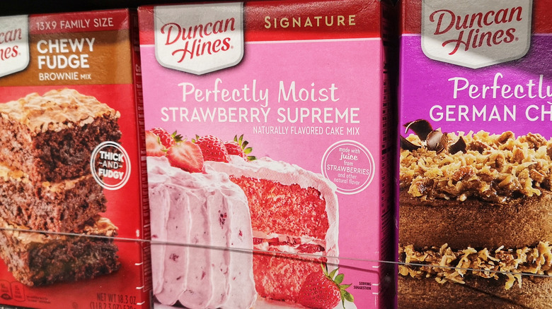 A box of Duncan Hines Signature Strawberry Supreme cake mix on a shelf between two other boxes