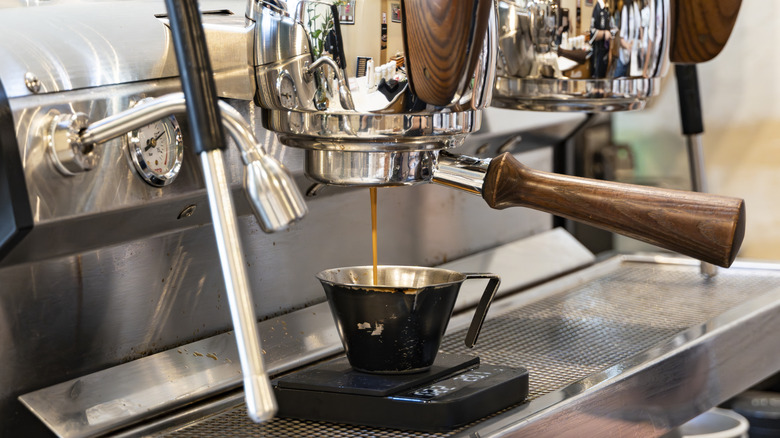 A high-end espresso machine pouring coffee into a small cup