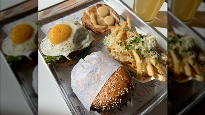 Two sandwiches and fries on a metal tray.