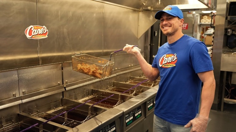 YouTuber in Raising Cane's kitchen holding frying basket
