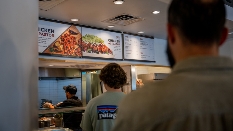 Customers waiting in line at a Chipotle restaurant