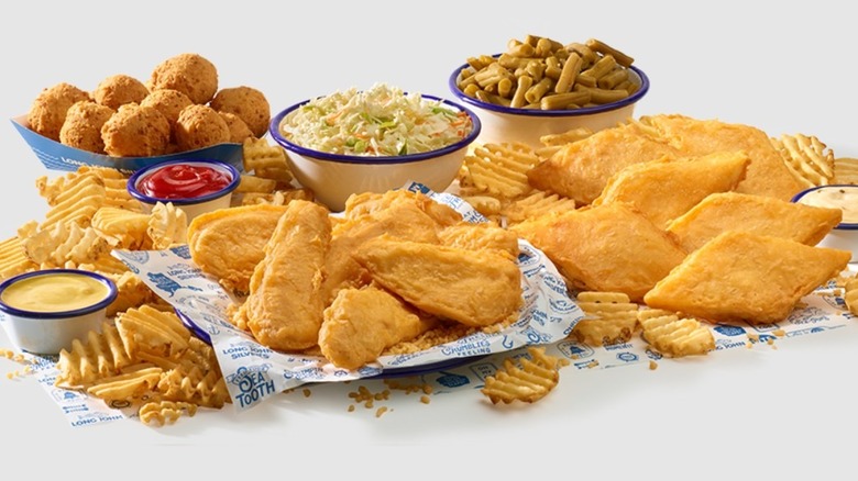 Long John Silver's fish and chicken pieces laid out alongside waffle fries, green beans, coleslaw, hushpuppies, and dipping sauces