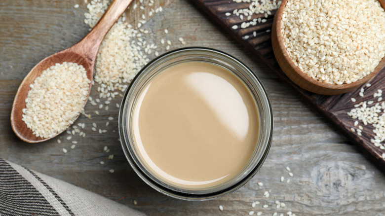 tahini in a bowl with sesame seeds around it