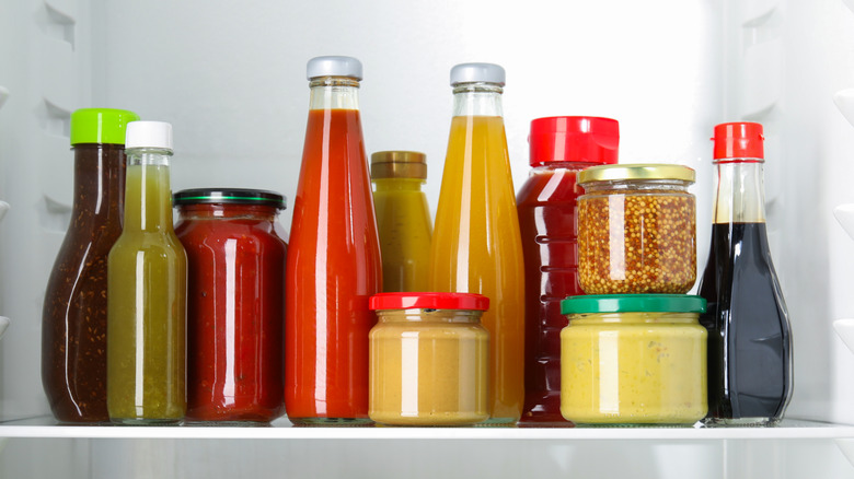 Bottles and jars of condiments on a refrigerator shelf