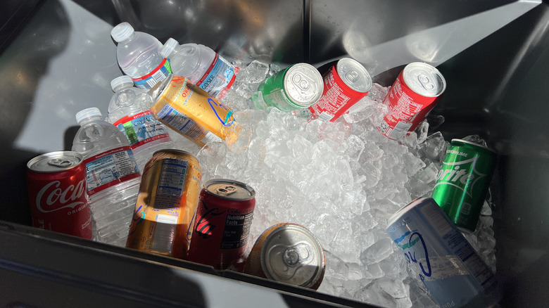 Various canned and bottled drinks in ice in a cooler