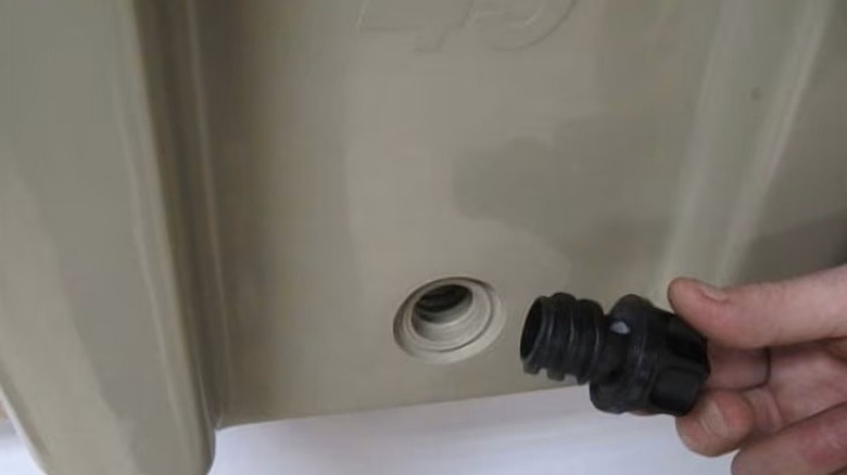 A hand holding a plug near a Yeti cooler