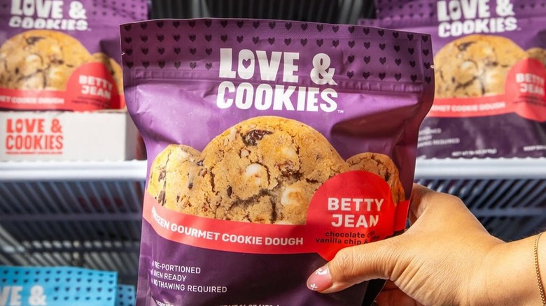 A hand holding a purple bag of Love & Cookies frozen gourmet cookie dough
