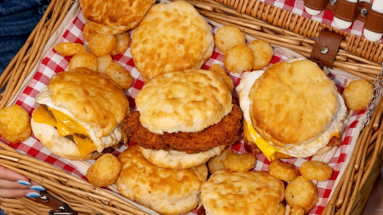 A variety of Hardee's breakfast biscuits and tater tots in a picnic basket