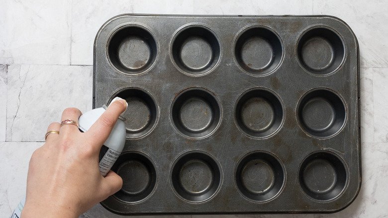Spraying muffin tin with oil