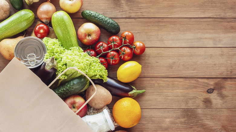Brown bag overflowing with groceries on a wooden table