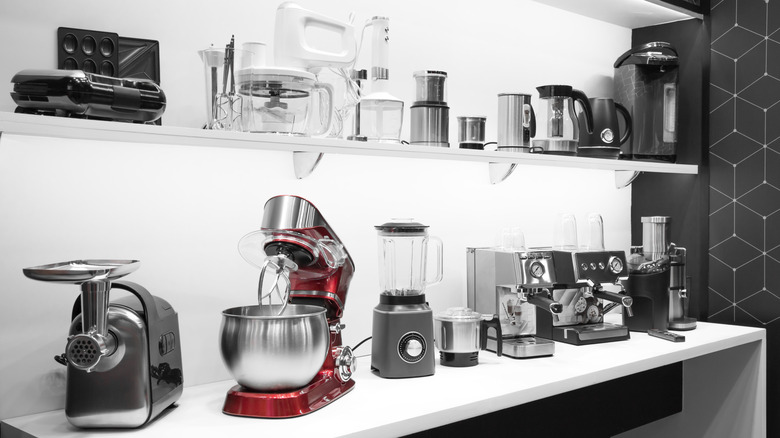 Several kitchen appliances including coffee machines and mixers arranged on a white counter