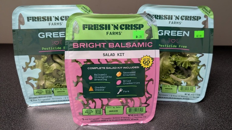 Plastic packs of greens from Fresh n' Crisp Farms on black table