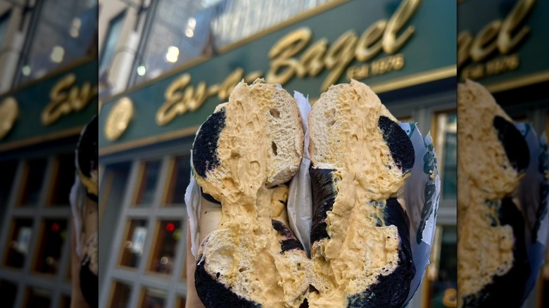 Bagel halves held in front of Ess-a-Bagel store