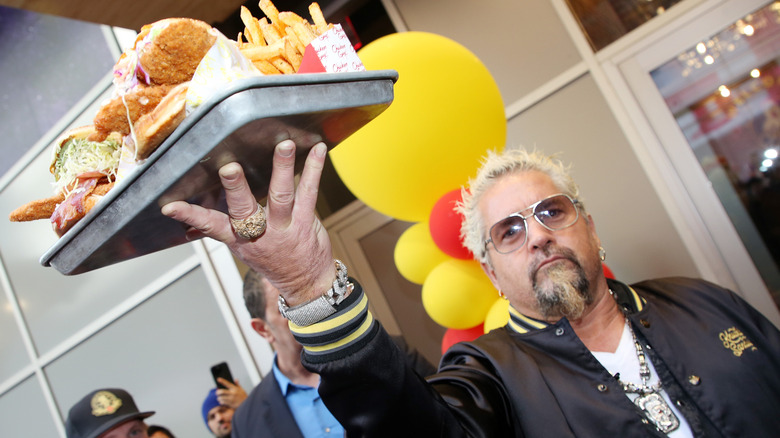 Guy Fieri holding a tray at the opening of his Chicken Guy! restaurant in Times Square in 2025