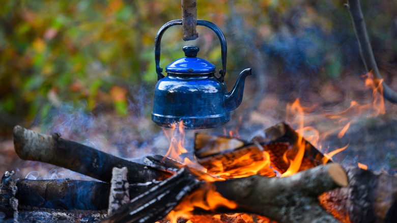 blue kettle hanging over campfire