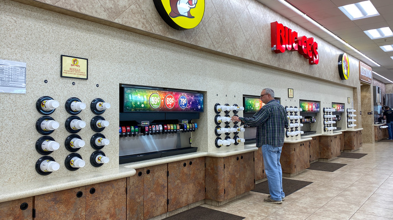 Wall of fountain soda machines at Buc-ee's with a customer choosing a cup