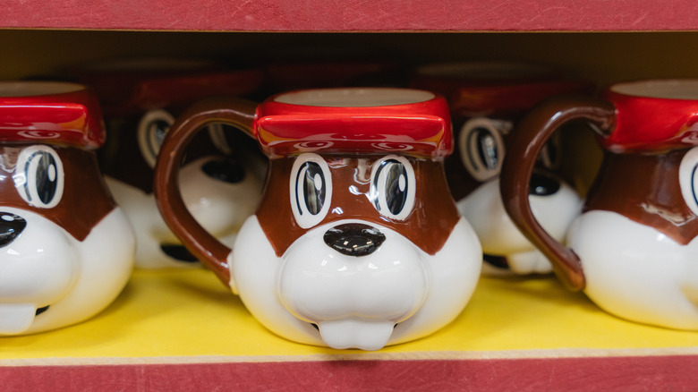 A collection of Buc-ee's ceramic coffee mugs on a yellow and red shelf