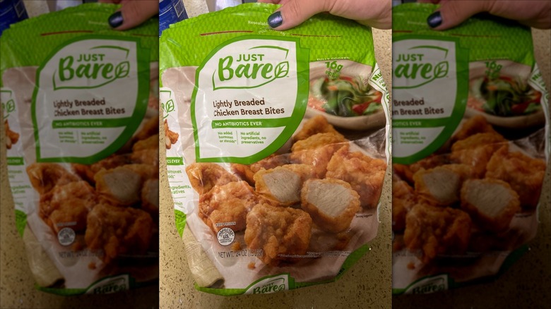 A woman's hand holding up a bag of Just Bare Lightly Breaded Chicken Breast Bites