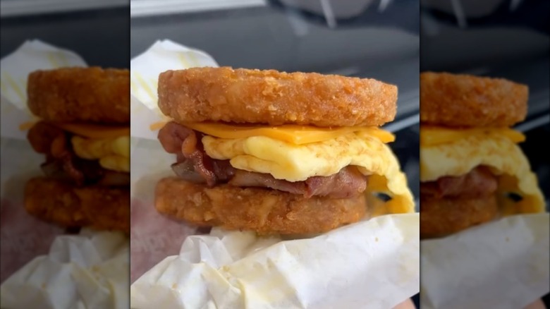 Bojangles Carolina Crunch sandwich with hash browns, cheese, eggs, and bacon held inside paper wrapper