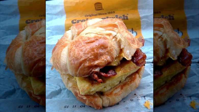 Burger King Double Candied Maple Bacon, Egg & Cheese Croissan'wich breakfast sandwich sitting on paper wrapping