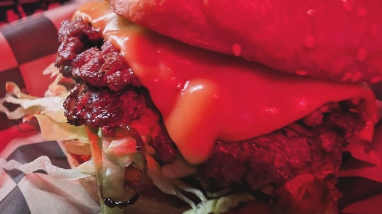 A close-up of a cheeseburger on a checkerboard surface at Kelly's