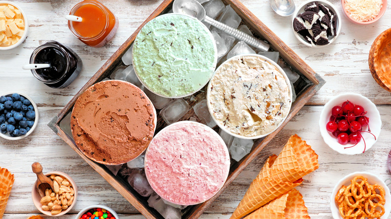 Open containers of ice cream surrounded by sundae toppings