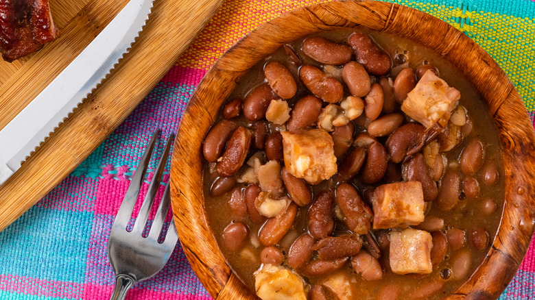 A bowl of baked beans with hunks of meat
