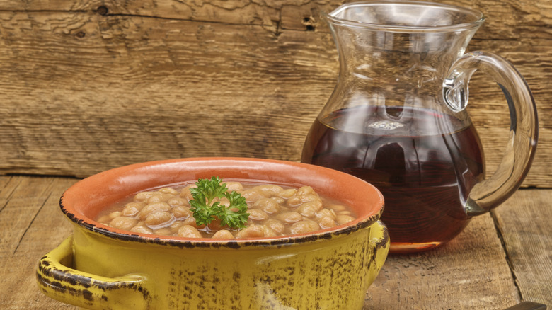 A bowl of baked beans and a clear pitcher of brown liquid