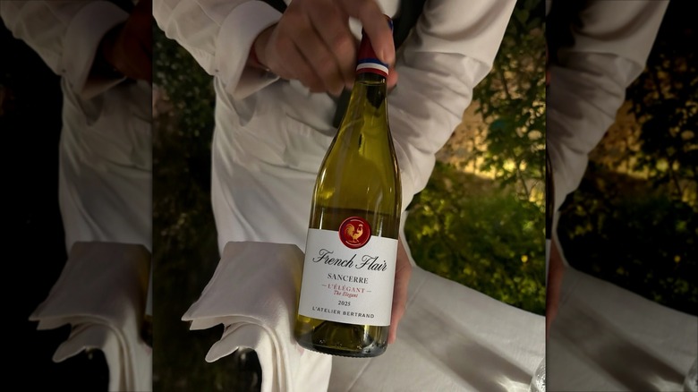A server displays a bottle of French Flair Sancerre L'Élégant wine