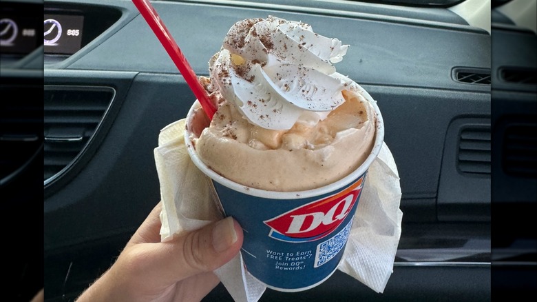 A small Dairy Queen Blizzard with whipped cream in a car