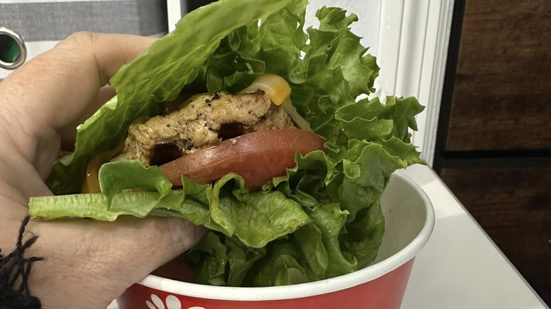 Person holds a Chick-fil-A sandwich with lettuce instead of bread
