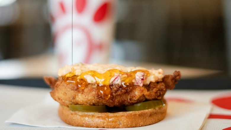 A close-up of a Chick-fil-A Chicken Sandwich slathered with honey and other sauces