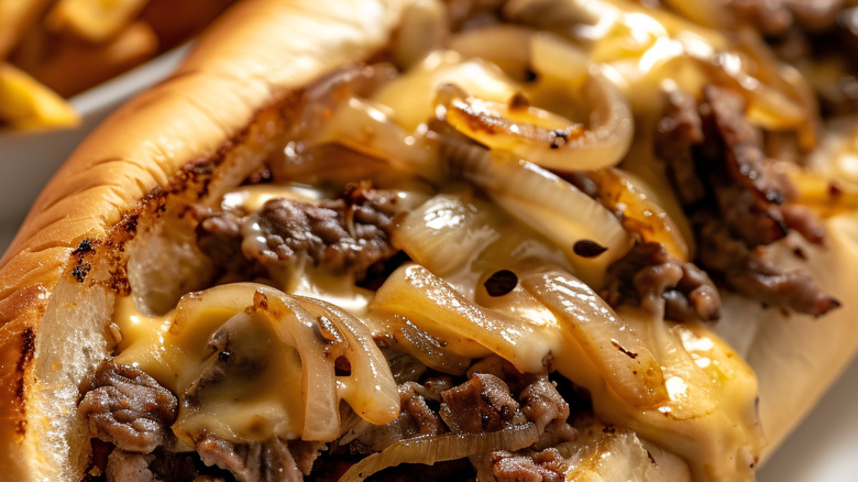 Close up of a cheesesteak with melted cheese and grilled onions
