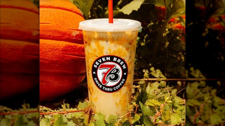 Pumpkin Blondie Breve iced coffee beverage from 7 Brew Coffee with orange pumpkin and leaves in background