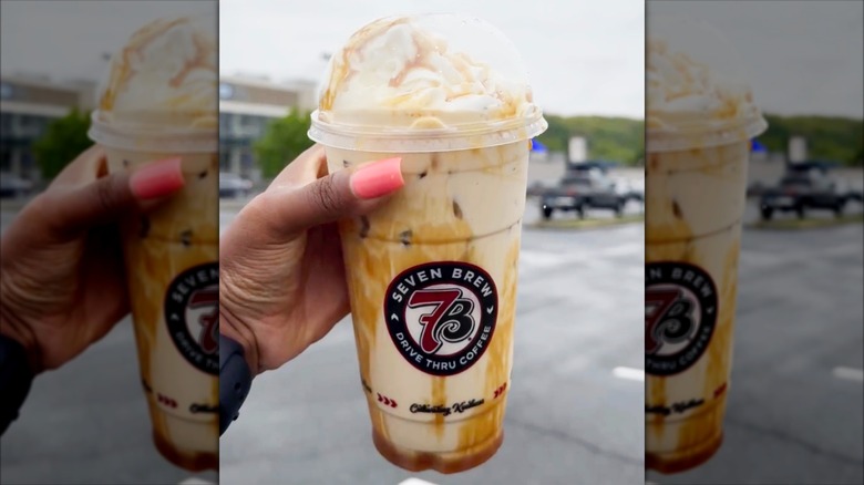 Hand holding strawberry cheesecake Blondie iced coffee with whipped cream from 7 Brew Coffee