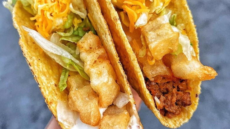 Close up of two hard shell tacos with fries and white sauce